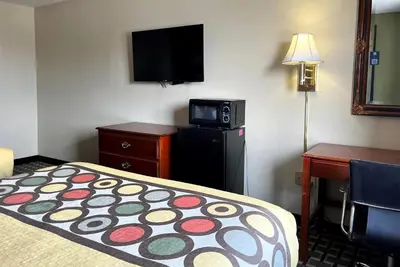 a hotel room with a bed and a flat screen tv at Super 8 by Wyndham Madison IN in Madison