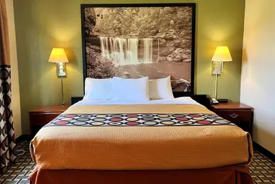 a hotel room with a bed with a painting on the wall at Super 8 by Wyndham Madison IN in Madison