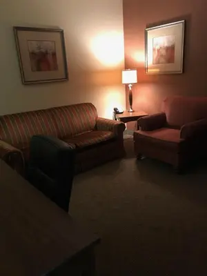 a hotel room with a couch and a chair and a lamp at Randolph Inn and Suites in Winchester