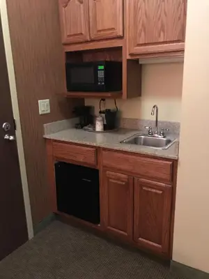 a small kitchen with a sink and a microwave at Randolph Inn and Suites in Winchester
