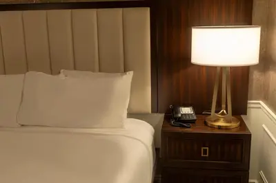 a bed with a lamp and a phone on a night stand at The Grand Resort in Howland Corners