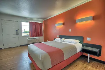 a large bed in a room with an orange wall at Motel 6-Lima, OH in Lima