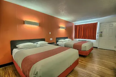 two beds in a hotel room with orange walls at Motel 6-Lima, OH in Lima