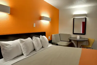 a hotel room with a bed with white pillows at Motel 6-Toledo, OH in Maumee