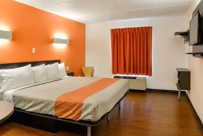 a hotel room with a bed with an orange wall at Motel 6-Toledo, OH in Maumee
