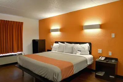 a hotel room with a bed with an orange wall at Motel 6-Toledo, OH in Maumee