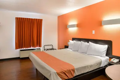a hotel room with a bed with an orange wall at Motel 6-Toledo, OH in Maumee