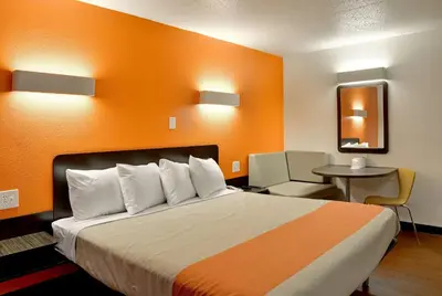 a hotel room with a bed with an orange wall at Motel 6-Toledo, OH in Maumee