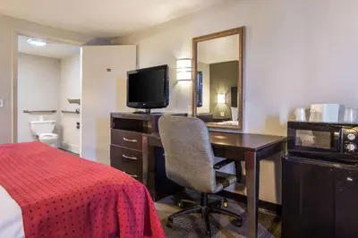 a hotel room with a desk and a bed and a mirror at Rodeway Inn Near Hall of Fame in Canton