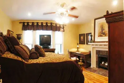 a bedroom with a bed with a ceiling fan and a fireplace at Gaslight Bed & Breakfast in Cincinnati