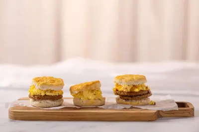 three sandwiches sitting on a wooden cutting board at Drury Inn & Suites Cincinnati Northeast Mason in Mason