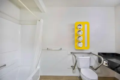 a bathroom with a toilet and a yellow sign on the wall at Motel 6 - Georgetown, KY - Lexington North in Georgetown