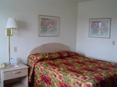 a hotel room with a bed and a nightstand with a lamp at Heritage Inn Mansfield in Mansfield