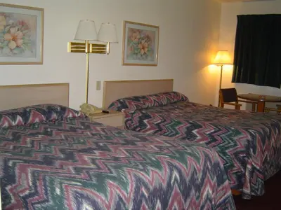 a hotel room with a bed and a desk with a phone at Heritage Inn Mansfield in Mansfield