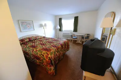 a hotel room with a bed and a flat screen tv at Heritage Inn Mansfield in Mansfield