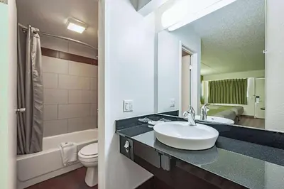 a bathroom with a sink and a toilet and a mirror at Days Inn by Wyndham Cincinnati I-71 in Cincinnati