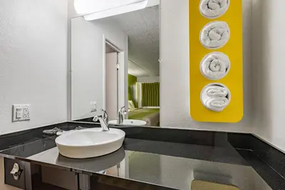 a bathroom with a sink and towels on the wall at Days Inn by Wyndham Cincinnati I-71 in Cincinnati