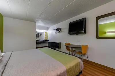 a room with a bed and a table and a tv at Days Inn by Wyndham Cincinnati I-71 in Cincinnati
