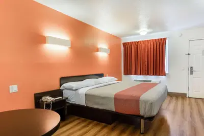 a hotel room with a bed with an orange wall at Motel 6-Youngstown, OH in Youngstown