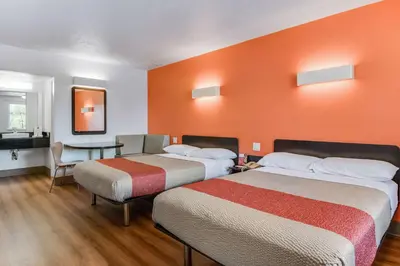 two beds in a room with an orange wall at Motel 6-Youngstown, OH in Youngstown