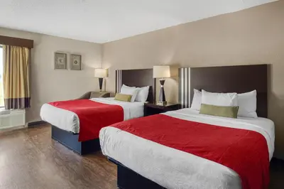 a hotel room with two beds with red sheets at SureStay by Best Western Greenville in Greenville
