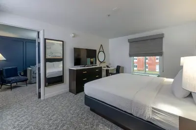 a bedroom with a bed and a desk and a mirror at The Ohioan Hotel and Event Center in Lewis Center