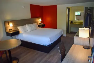 a hotel room with a large bed and a table at Ramada by Wyndham Cleveland Airport West in Fairview Park