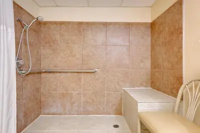 a bathroom with a shower with a bench in it at Ramada by Wyndham Cleveland Airport West in Fairview Park