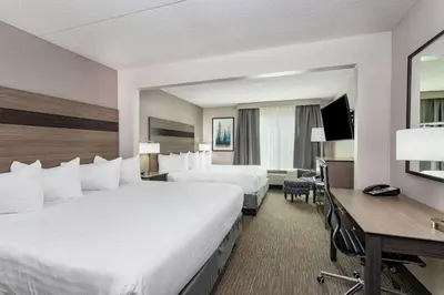 a hotel room with two beds and a desk at Wingate by Wyndham Lima in Lima