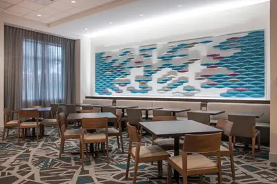 a dining room with tables and chairs and a large painting at Fairfield by Marriott Inn & Suites Dayton Downtown in Dayton