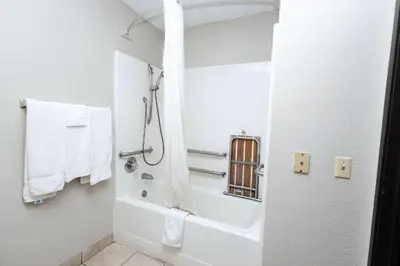 a white bathroom with a tub and a shower with towels at Days Inn by Wyndham Dayton Huber Heights Northeast in Huber Heights