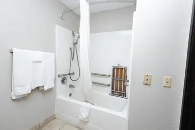 a bathroom with a tub and a shower with towels at Days Inn by Wyndham Dayton Huber Heights Northeast in Huber Heights