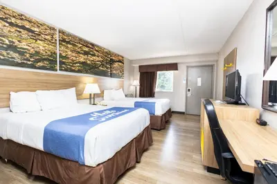 a hotel room with two beds and a flat screen tv at Days Inn by Wyndham Dayton Huber Heights Northeast in Huber Heights