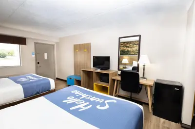 a hotel room with two beds and a desk and a television at Days Inn by Wyndham Dayton Huber Heights Northeast in Huber Heights