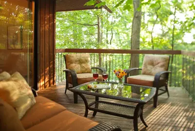 a screened in porch with a table and glasses of wine at The Inn at Honey Run Millersburg in Millersburg