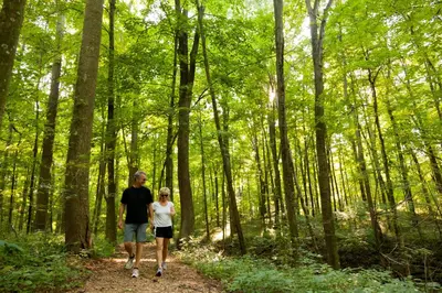 a man and woman walking down a trail in the woods at The Inn at Honey Run Millersburg in Millersburg