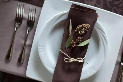 a plate with a brown napkin with a flower on it at The Inn at Honey Run Millersburg in Millersburg
