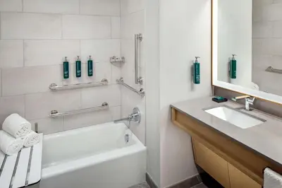 a bathroom with a white tub and a sink and a mirror at Hilton Columbus Downtown in Columbus