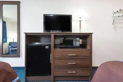 a television on a entertainment center with a microwave at Super 8 by Wyndham Greenfield in Greenfield