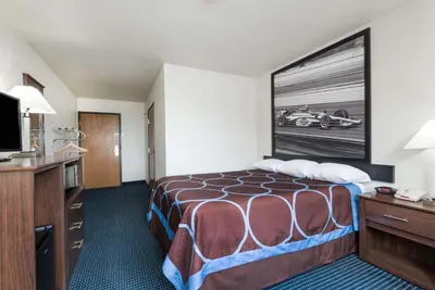 a hotel room with a bed and a flat screen tv at Super 8 by Wyndham Greenfield in Greenfield