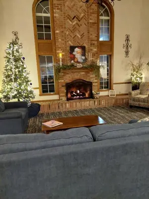 a living room with a blue couch and a christmas tree at Super 8 by Wyndham Greenfield in Greenfield