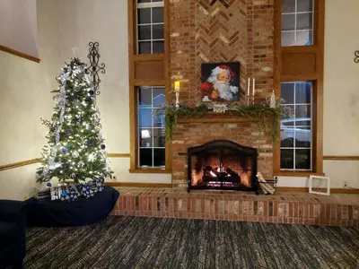 a living room with a christmas tree and a fireplace at Super 8 by Wyndham Greenfield in Greenfield