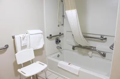 a bathroom with a tub and a toilet and a chair at Baymont by Wyndham Springfield in Springfield