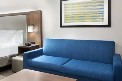 a blue couch in a hotel room with a bed at Holiday Inn Express & Suites - Columbus Airport East by IHG in Columbus