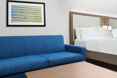 a hotel room with a blue couch and a bed at Holiday Inn Express & Suites - Columbus Airport East by IHG in Columbus