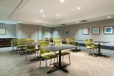 a waiting room with tables and chairs in a building at Holiday Inn Express & Suites - Columbus Airport East by IHG in Columbus
