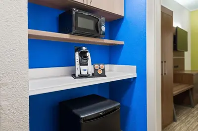 a room with a blue wall and a tv on a shelf at Holiday Inn Express & Suites - Columbus Airport East by IHG in Columbus