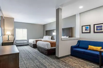 a hotel room with a bed and a blue couch at Comfort Suites Grove City - Columbus South in Grove City