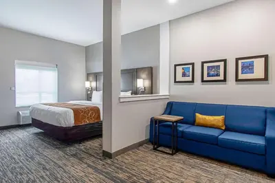 a hotel room with a bed and a blue couch at Comfort Suites Grove City - Columbus South in Grove City