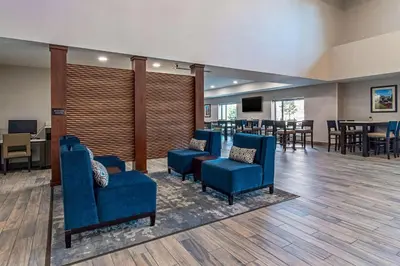 a waiting room with blue chairs and a table at Comfort Suites Grove City - Columbus South in Grove City